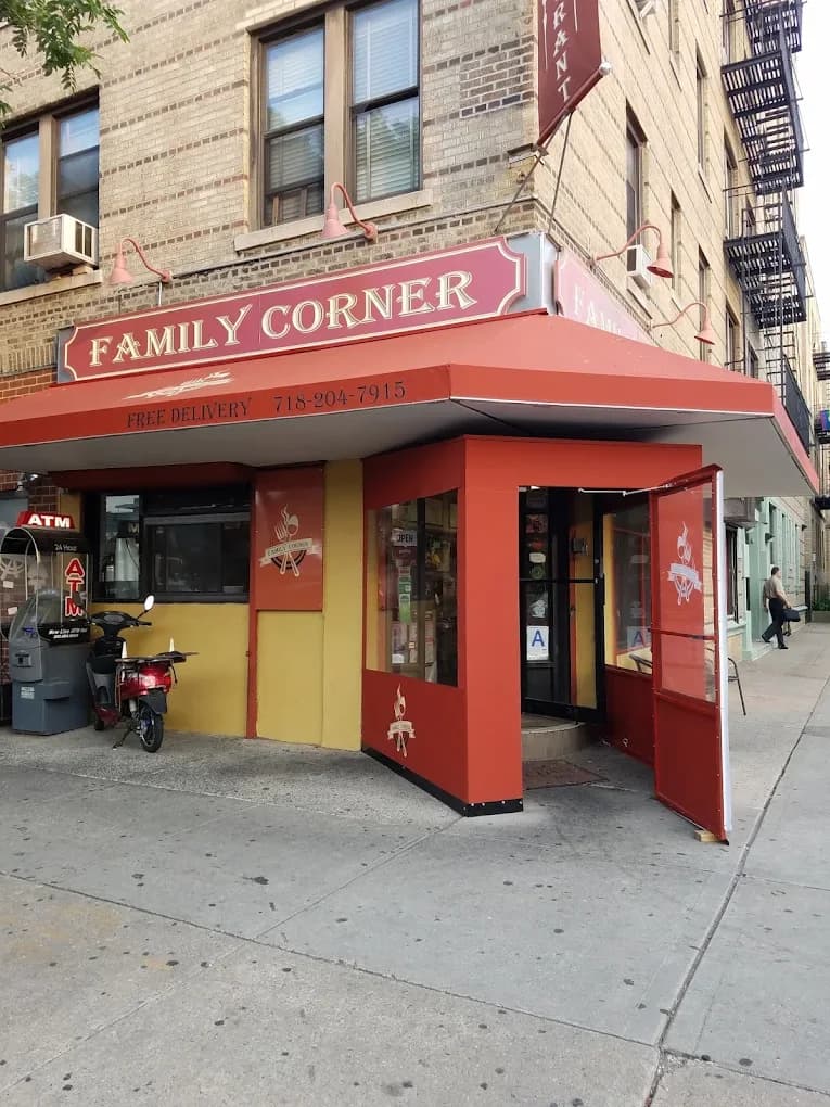 The Family Corner Restaurant storefront in Astoria, a red and yellow corner diner built into a residential apartment building with a free delivery sign on the awning