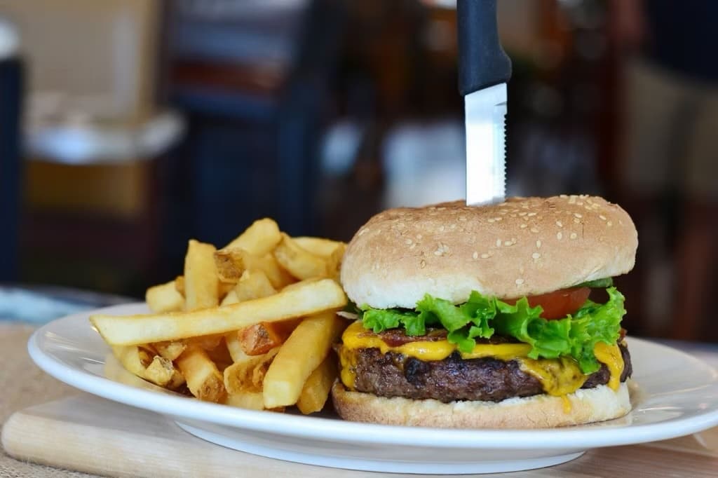 Court Square Diner classic cheeseburger with crispy fries and steak knife on a white plate