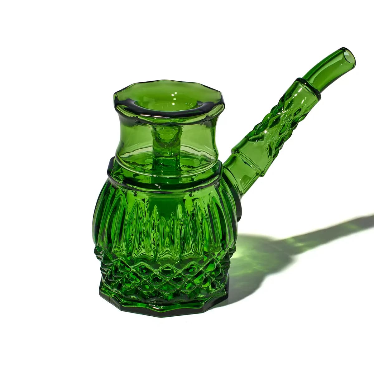 A green cut glass bubbler with a diamond pattern base and an angled mouthpiece, casting a green shadow