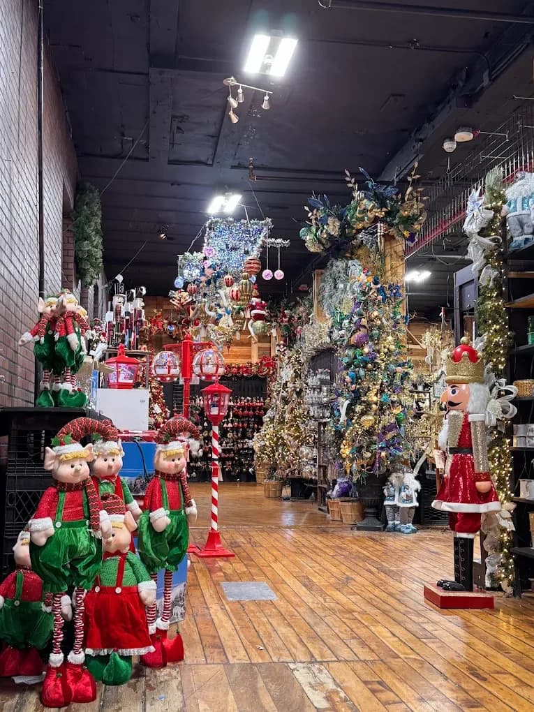 Inside House of Holiday, a year round Christmas store in Queens, with life sized elf figures, a nutcracker, decorated trees and hanging ornaments along a wood floor aisle