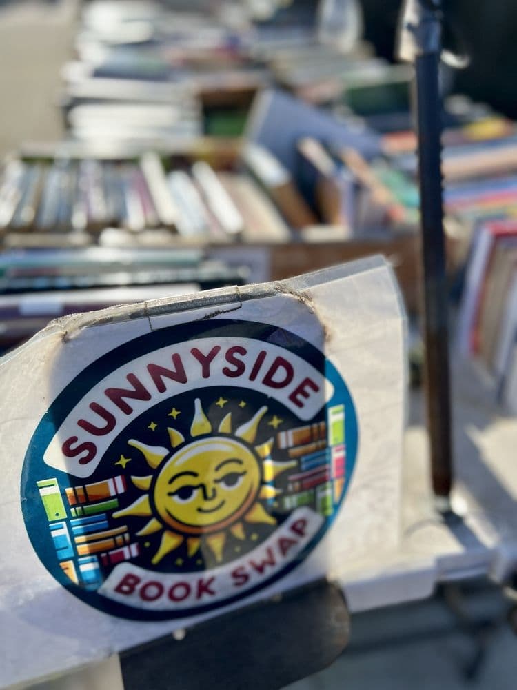 Sunnyside Book and Media Swap community stand in Queens with tables of used books, DVDs, and media to trade or donate