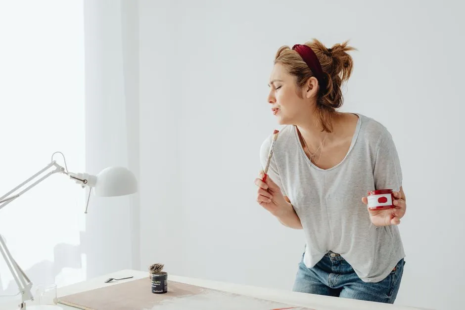 Person smiling and painting, appearing relaxed and creative. Alt text: