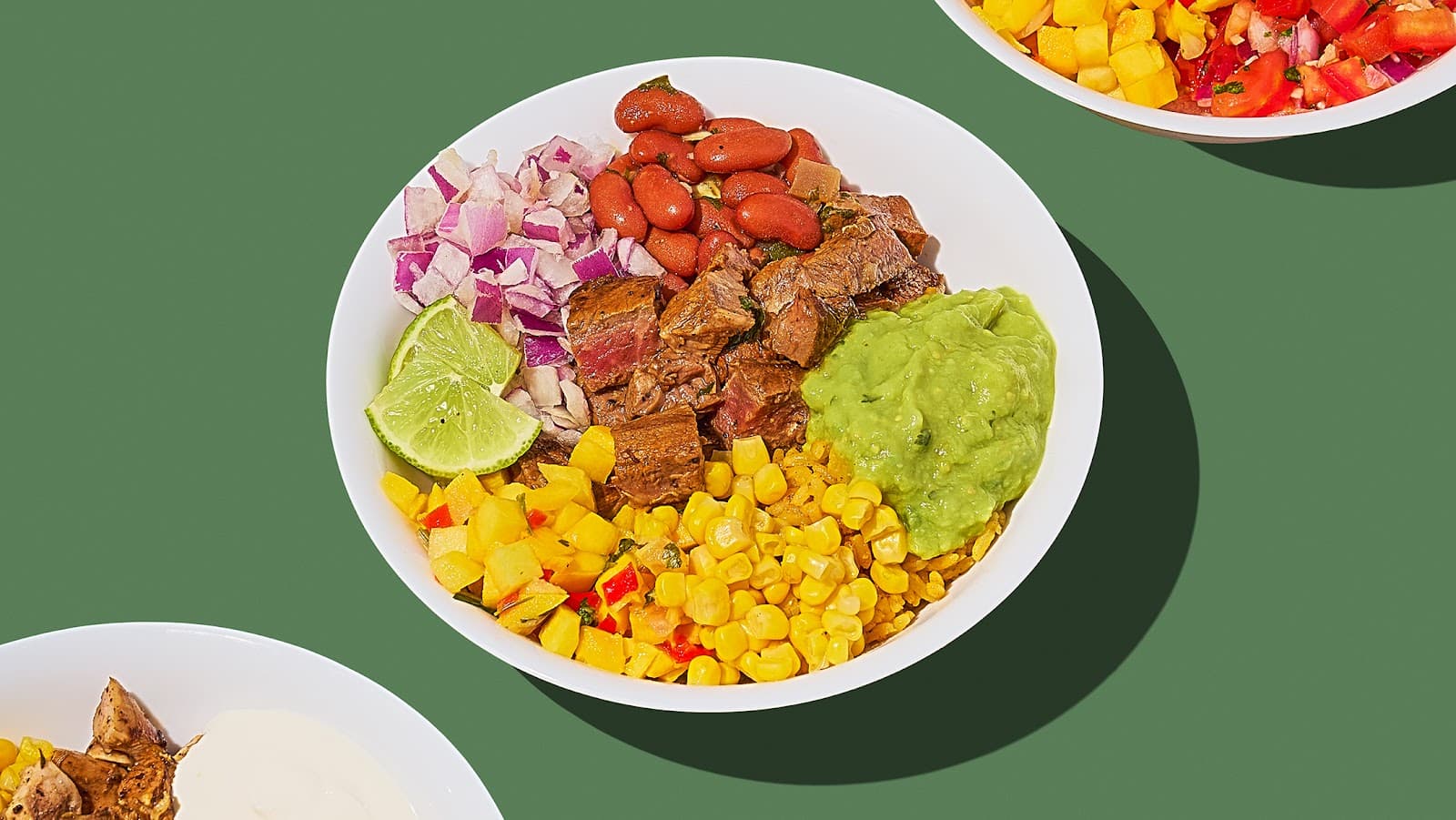 A build your own bowl from Bowl Bites in Ozone Park with steak, rice, red beans, corn, mango salsa, red onion, guacamole, and a lime wedge